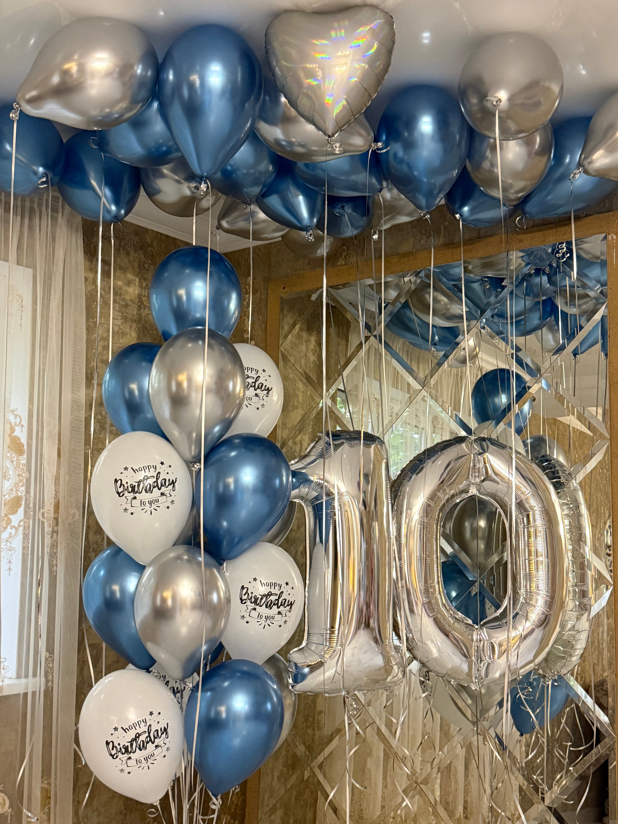 Elegant 10th birthday room decoration featuring metallic blue and silver helium ceiling balloons, silver foil number 10 balloons, white printed birthday balloons, and coordinating floating balloon bouquets by Best Balloons LA.