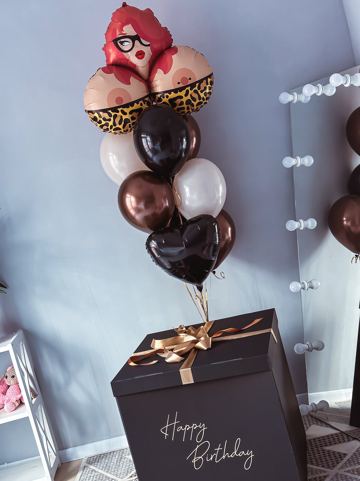Black Happy Birthday gift box with black, bronze, ivory, and heart-shaped helium balloons topped with a playful glam girl foil balloon.