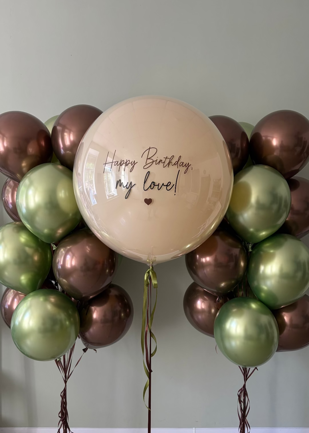 Large personalized birthday balloon with matching chrome balloon bouquets in olive green and bronze tones, styled as an elegant romantic birthday arrangement.