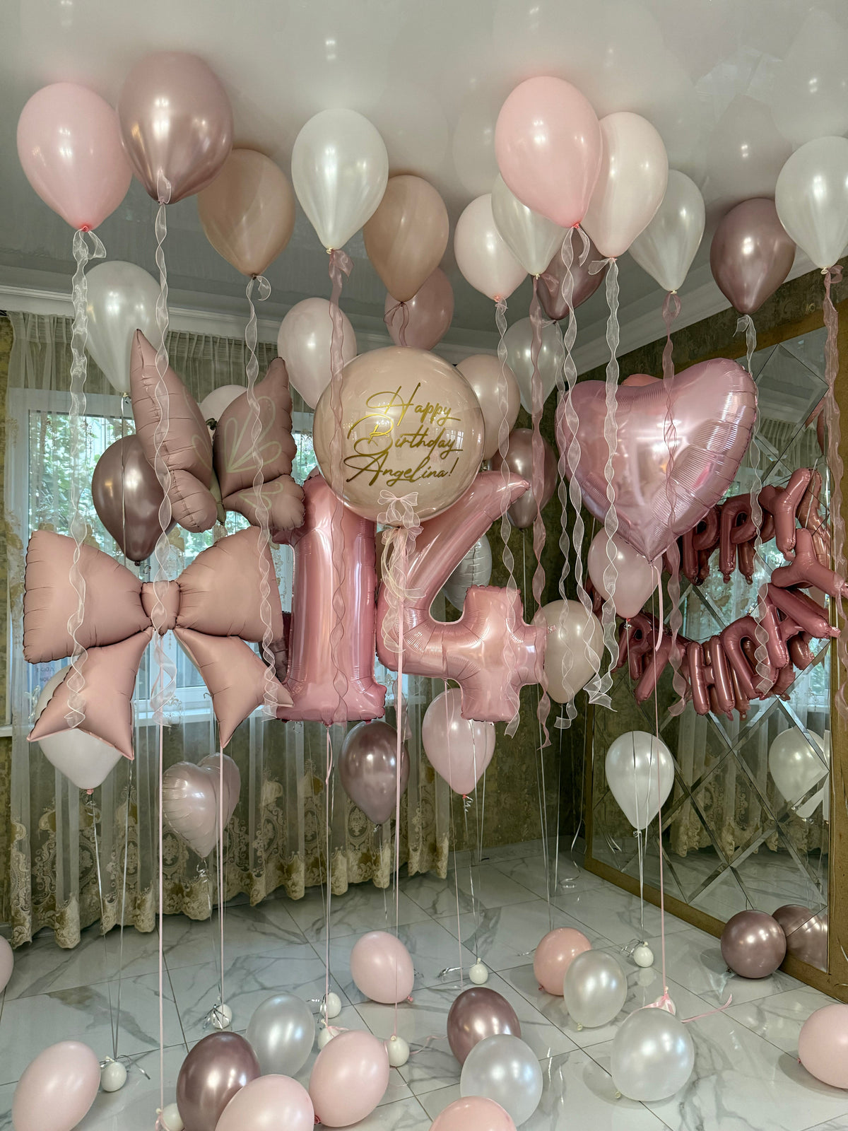 Luxury 14th birthday balloon room decoration featuring blush pink, champagne, rose gold, and pearl white helium balloons, oversized pink number 14 balloons, satin-style bow balloons, pink foil hearts, personalized Happy Birthday Angelina balloon, and elegant ceiling ribbons by Best Balloons LA.